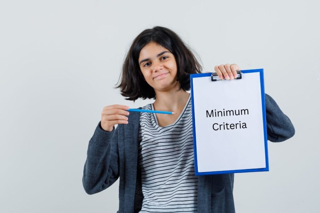 little girl in t-shirt & jacket pointing a clipboard showing minimum criteria