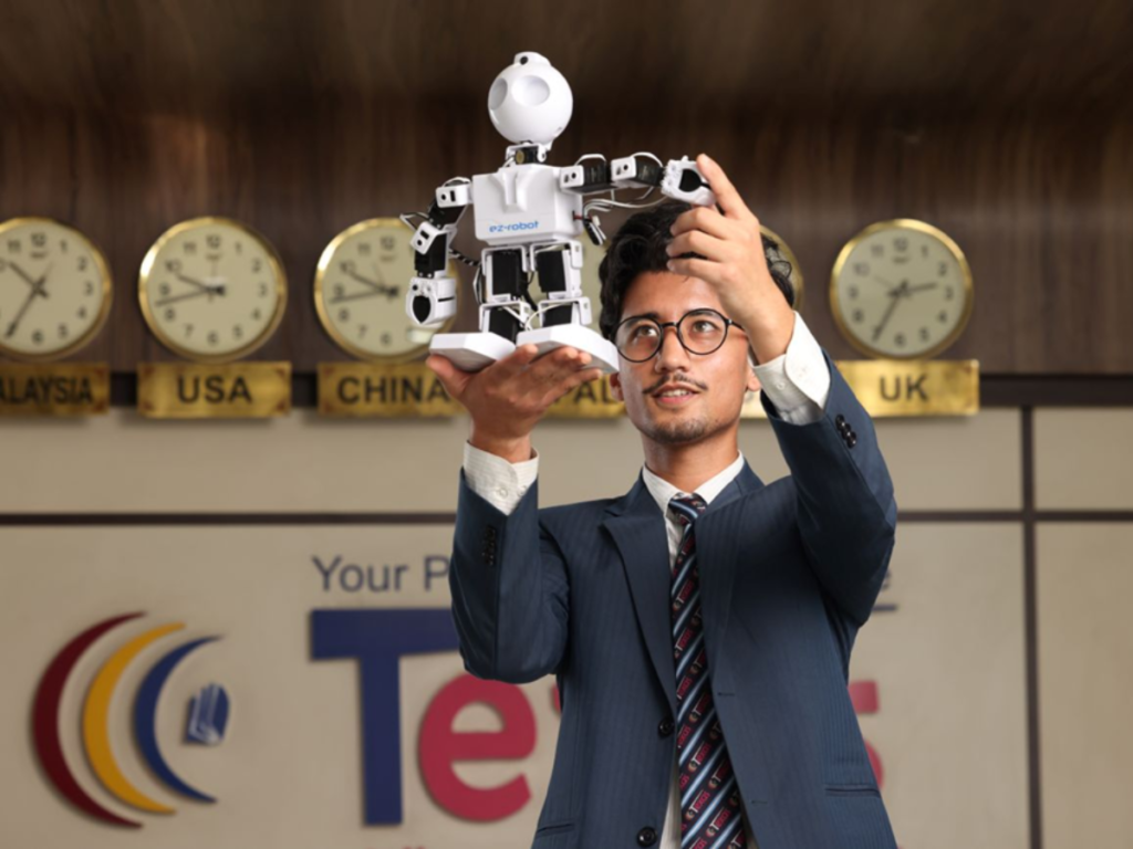 man showcasing the white robots in by lifting the robot in hand at texas college of management and it