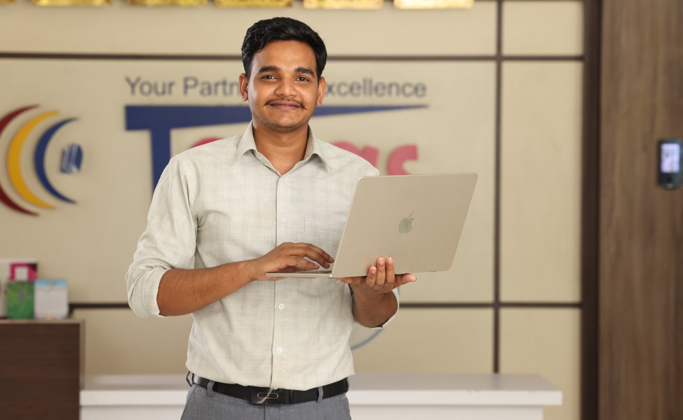 A men is standing by holding his laptop.